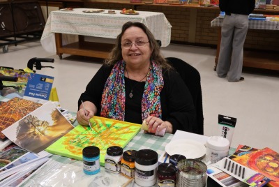 A woman sitting at a table and working on a painting