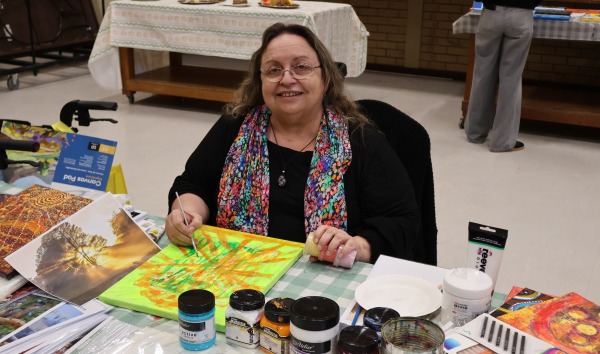 A woman sitting at a table and working on a painting