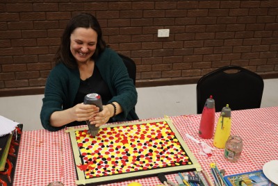 A woman sitting at a table and making a piece of artwork