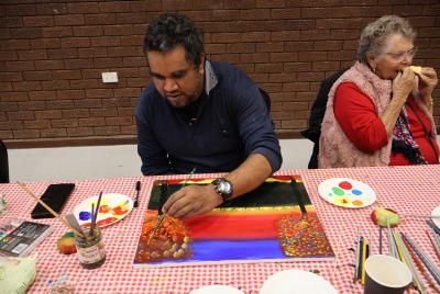 A man sitting at a table and painting as part of Heart and Soul
