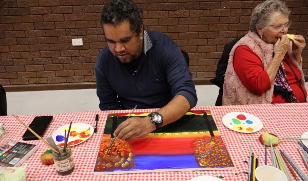 A man sitting at a table and painting as part of Heart and Soul